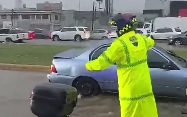 Agente de la Digesett dirige tránsito en calle inundada durante lluvias